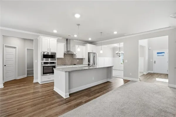a kitchen with stainless steel appliances kitchen island granite countertop a refrigerator and a sink