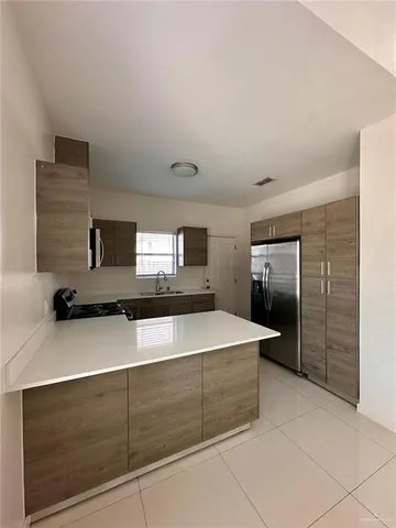 a kitchen with kitchen island sink and refrigerator