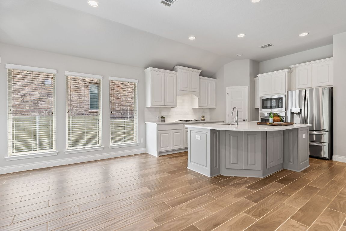 3604 Mercer Road Georgetown, TX 78628 - Photo 15 of 39 a kitchen with stainless steel appliances granite countertop a stove a sink a refrigerator and white cabinets with wooden floor