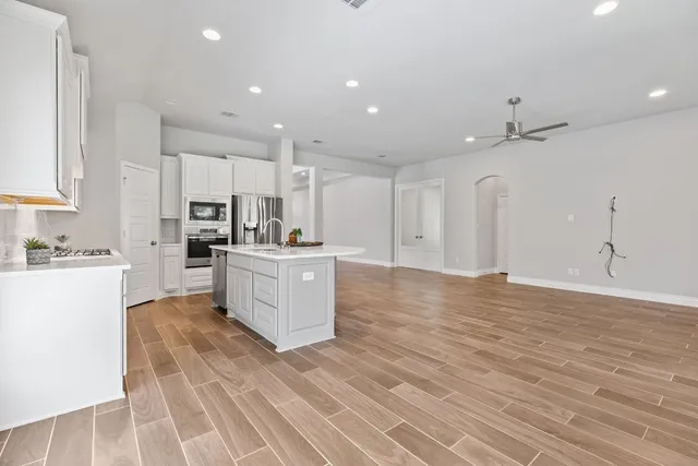 a large white kitchen with kitchen island a sink a stove a refrigerator and white cabinets