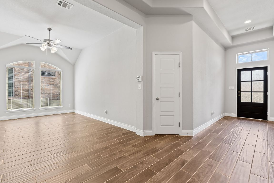 3604 Mercer Road Georgetown, TX 78628 - Photo 7 of 39 an empty room with wooden floor chandelier fan and windows