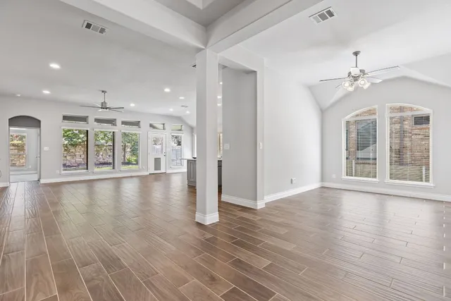 an empty room with wooden floor and windows