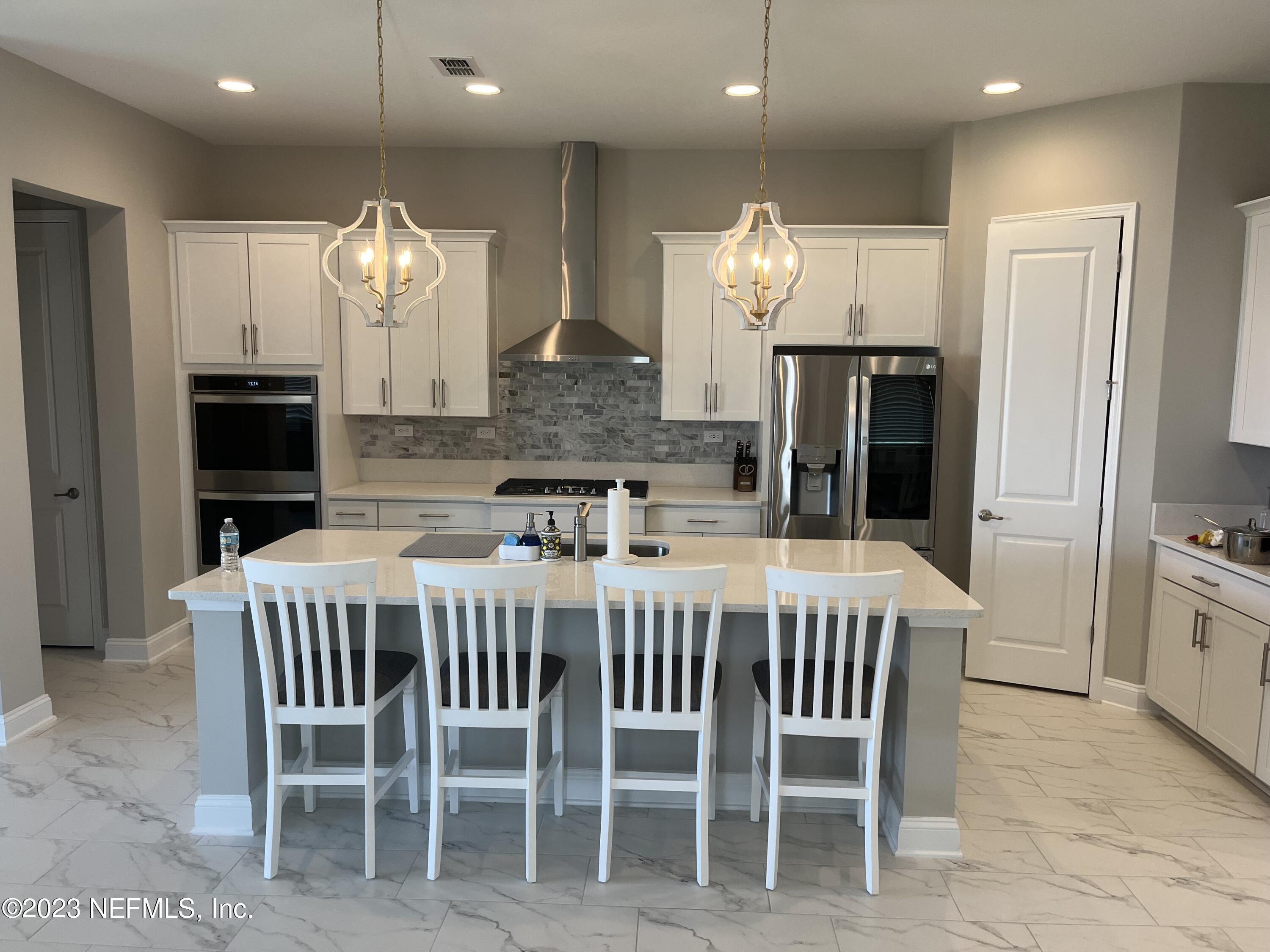 481 Marquesa Circle St. Johns, FL 32259 - Photo 7 of 53 a kitchen with stainless steel appliances kitchen island granite countertop a table chairs sink and cabinets