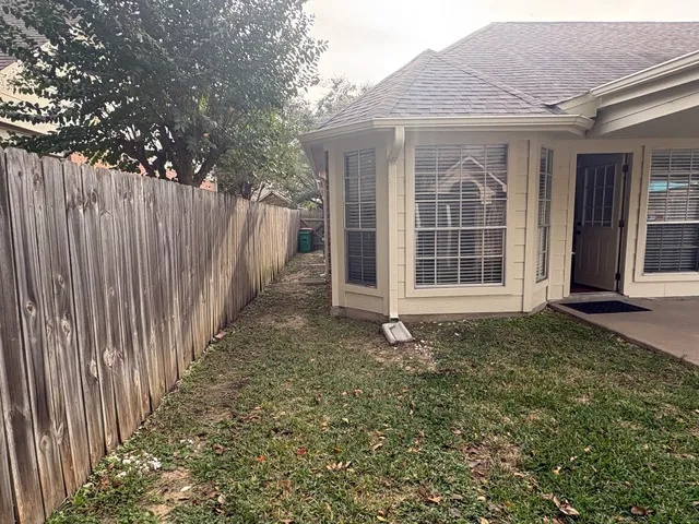 a view of a house with a small yard and wooden floor and fence