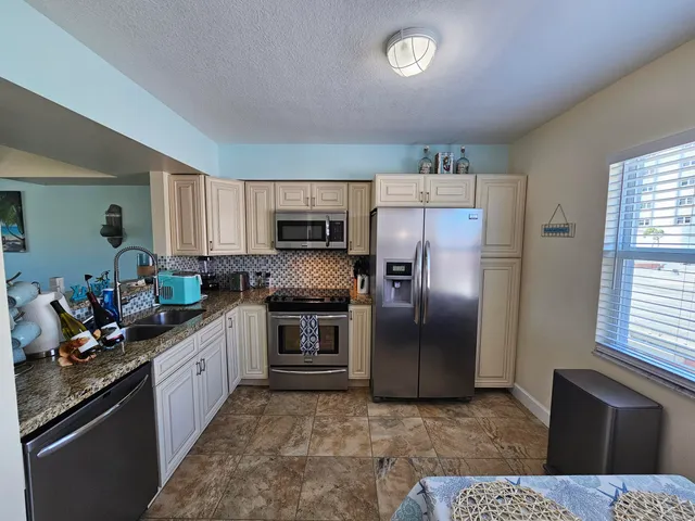 a kitchen with stainless steel appliances kitchen island granite countertop a refrigerator stove top oven and sink