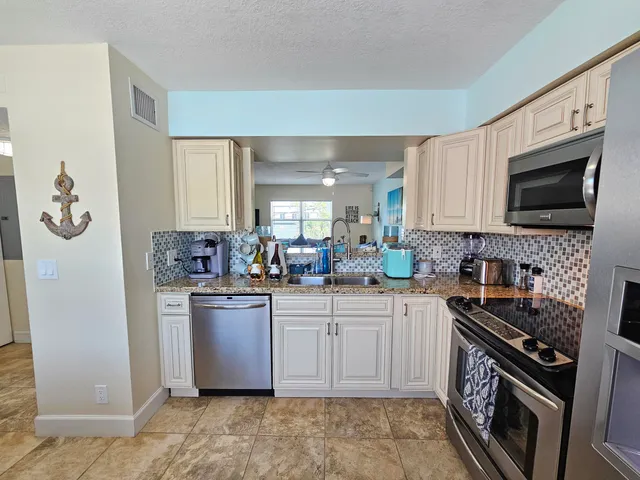 a kitchen with stainless steel appliances granite countertop a stove top oven a sink dishwasher and a microwave oven on the blue kitchen countertops