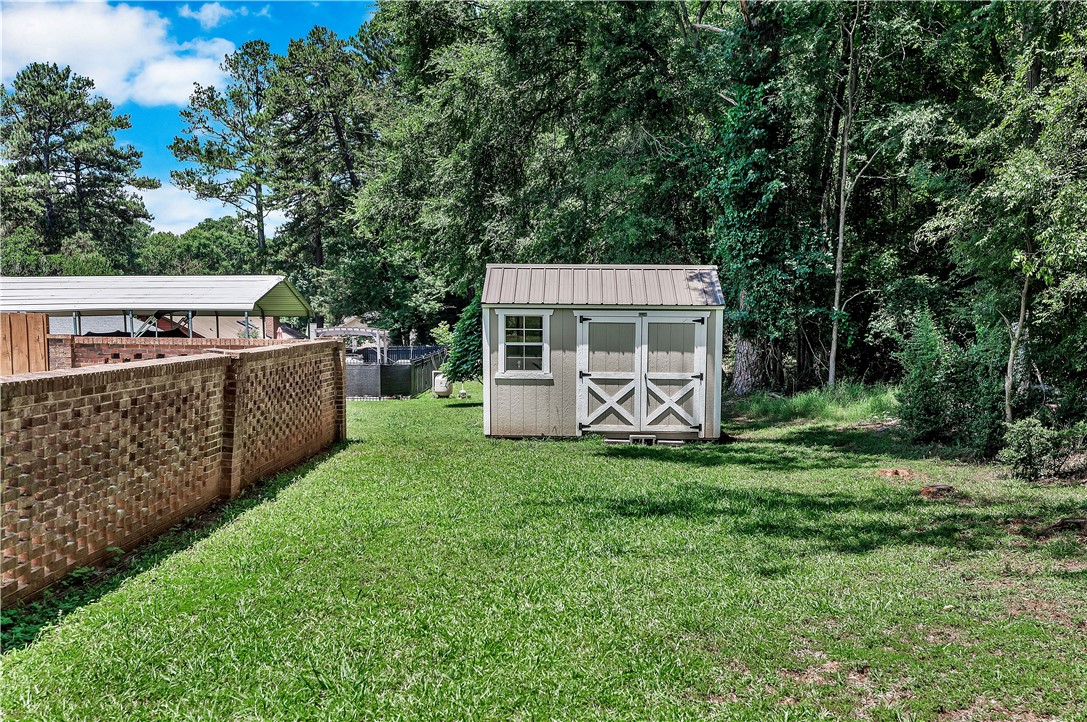 910 Chantilly Lane Anderson, SC 29625 - Photo 35 of 38 A well-maintained lawn with a storage shed, bordered by a decorative brick fence.