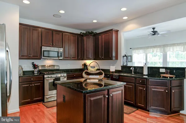 a kitchen with kitchen island granite countertop a sink dishwasher stove and cabinets