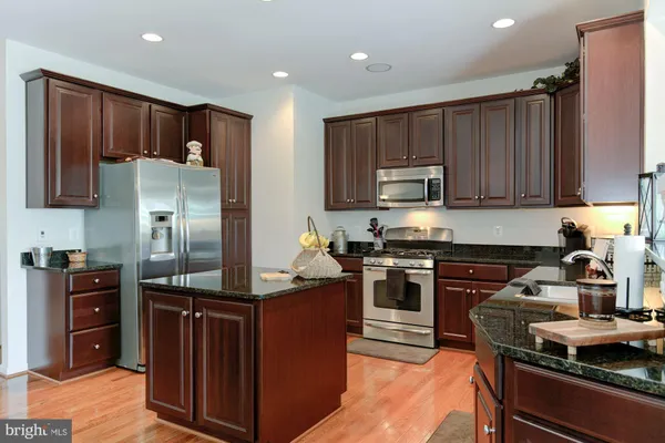 a kitchen with kitchen island granite countertop stainless steel appliances and wooden cabinets