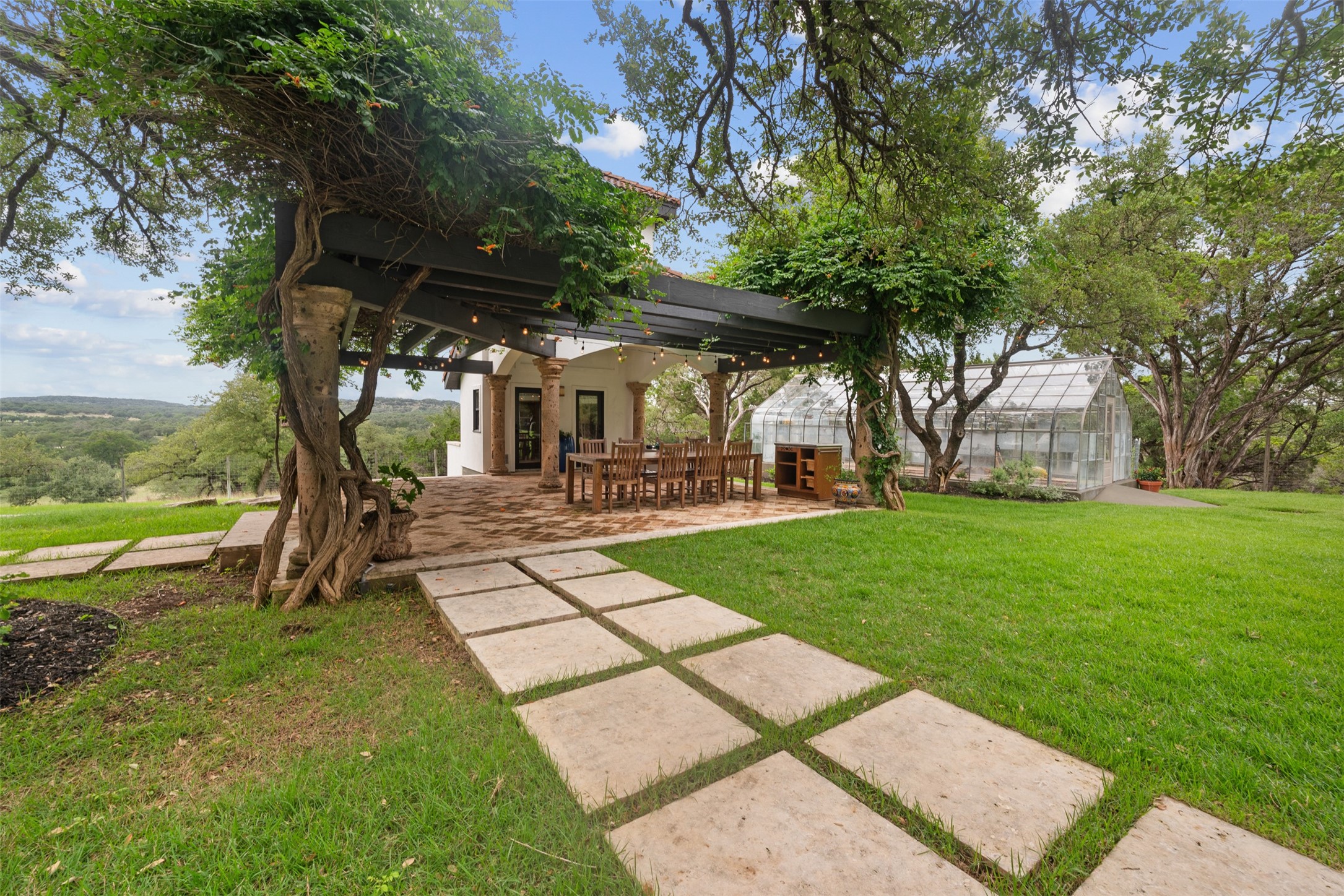 34000 Smithson Valley Road Bulverde, TX 78163 - Photo 35 of 50 A vine-covered pergola creates an inviting outdoor dining experience with picturesque views of the surrounding countryside. The nearby greenhouse adds charm and functionality to this exceptional outdoor retreat.