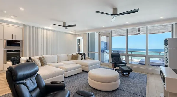 a living room with furniture a ceiling fan and a large window