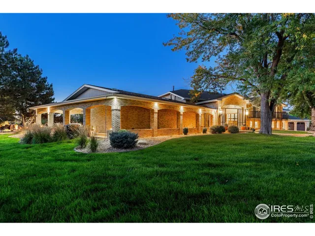 a backyard of a house with table and chairs plants and large tree