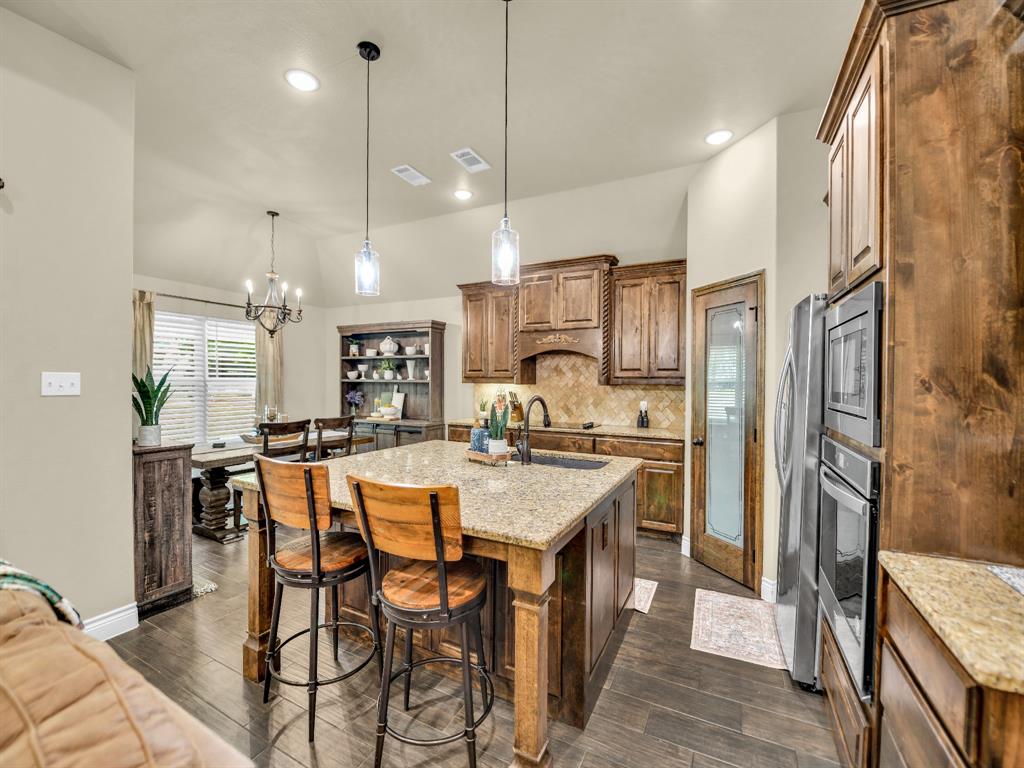 156 Cottongame Road Weatherford, TX 76088 - Photo 8 of 35 a kitchen with stainless steel appliances kitchen island granite countertop a refrigerator a oven a sink with a dining table and chairs