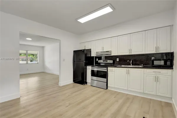 a kitchen with granite countertop a refrigerator and a stove top oven