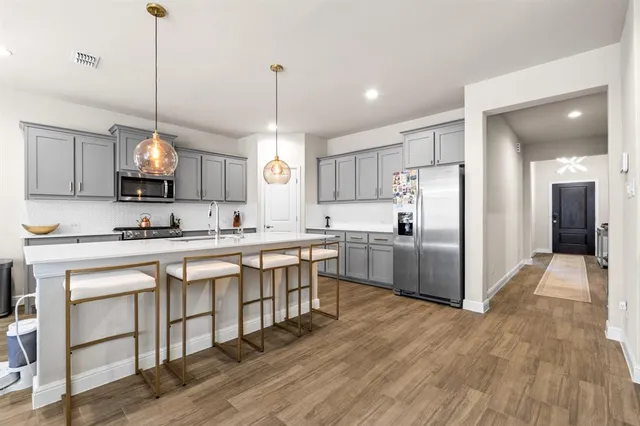 a kitchen with stainless steel appliances granite countertop a sink a stove a refrigerator and island with wooden floor