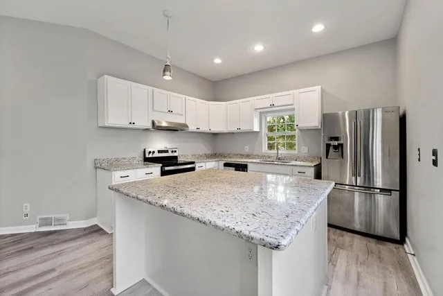 a kitchen with stainless steel appliances granite countertop a refrigerator a stove a sink and a refrigerator