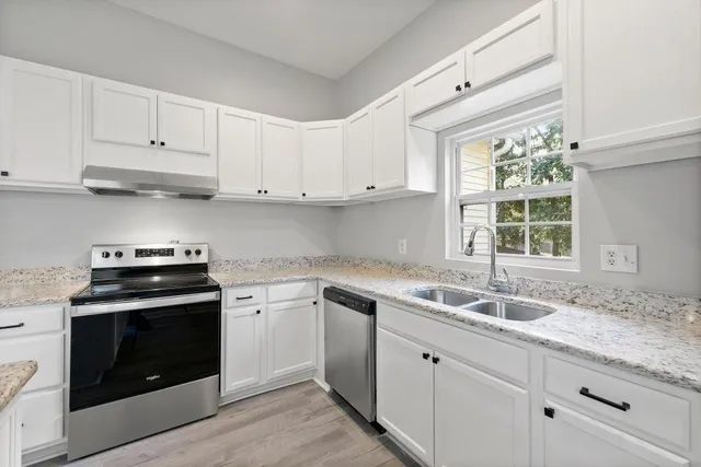 a kitchen with granite countertop white cabinets and a stove