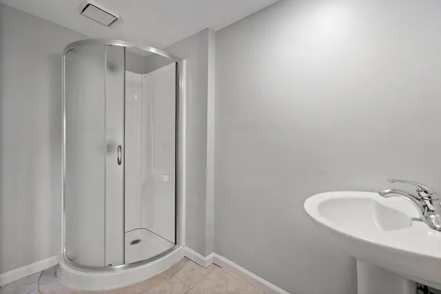 a bathroom with a sink shower and a mirror