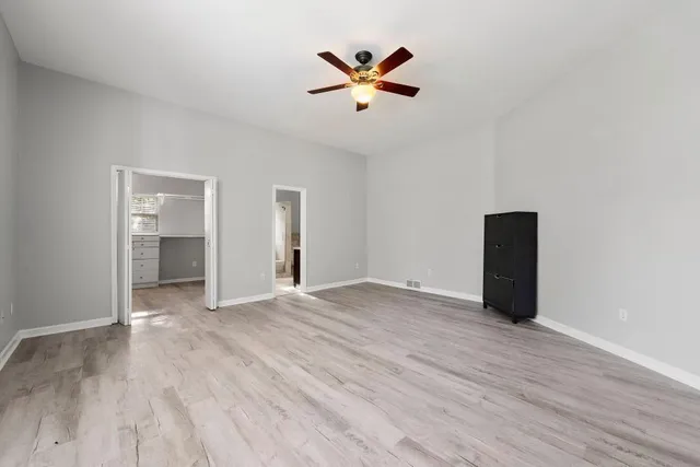 an empty room with closet and a ceiling fan