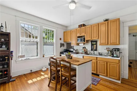 a kitchen with stainless steel appliances granite countertop a stove a refrigerator a sink a dining table and chairs with wooden floor