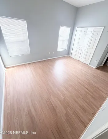 an empty room with wooden floor and windows
