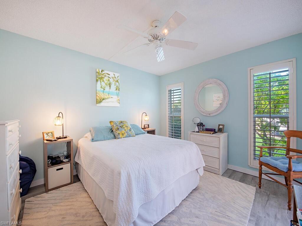 53 High Point Circle West, Unit 101 Naples, FL 34103 - Photo 8 of 18 a bedroom with a large bed and a chandelier
