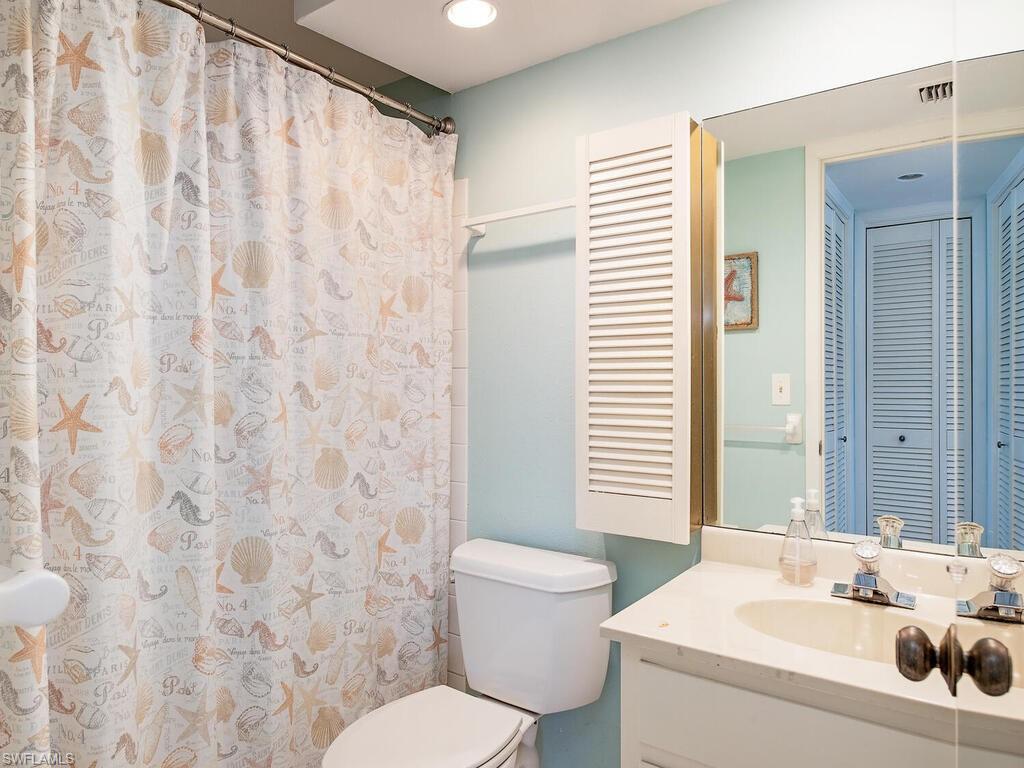 53 High Point Circle West, Unit 101 Naples, FL 34103 - Photo 9 of 18 a bathroom with a sink a toilet and shower curtain