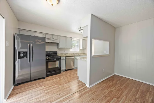 a kitchen with granite countertop a refrigerator and a stove top oven