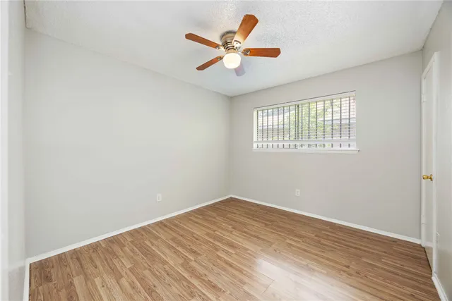an empty room with wooden floor and ceiling fan