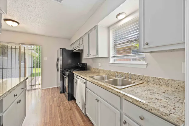 a kitchen with granite countertop a sink stove and refrigerator