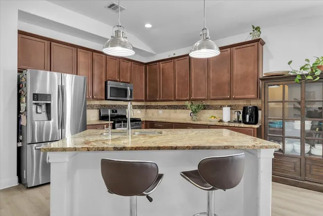 a kitchen with stainless steel appliances granite countertop a sink refrigerator and cabinets
