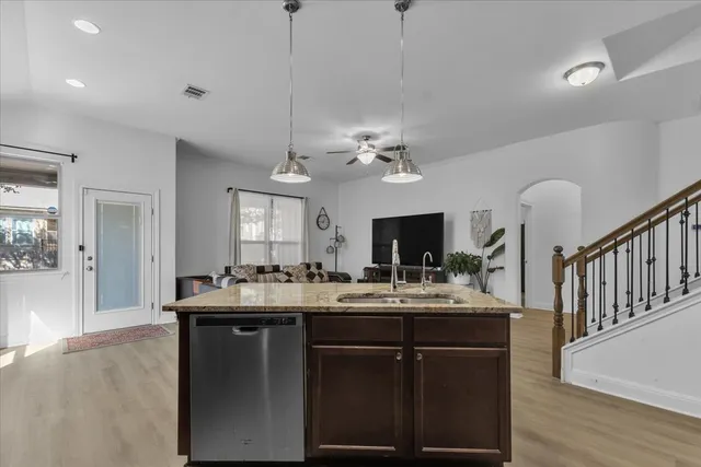 a kitchen with kitchen island granite countertop a sink a counter top space and living room view