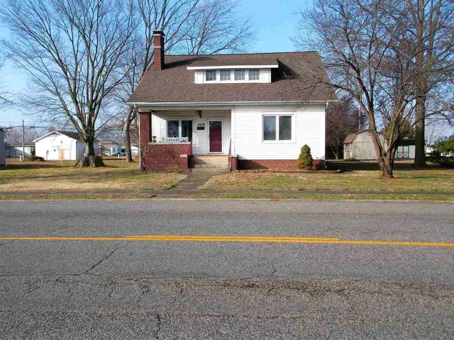 a view of a house with a yard and large trees