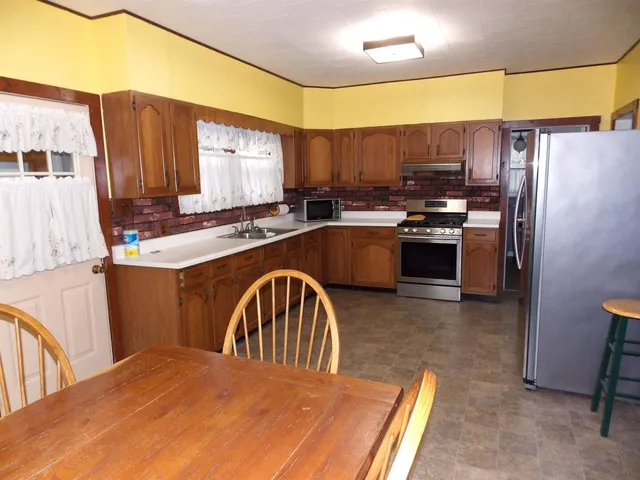 a kitchen with stainless steel appliances granite countertop a sink refrigerator stove and microwave