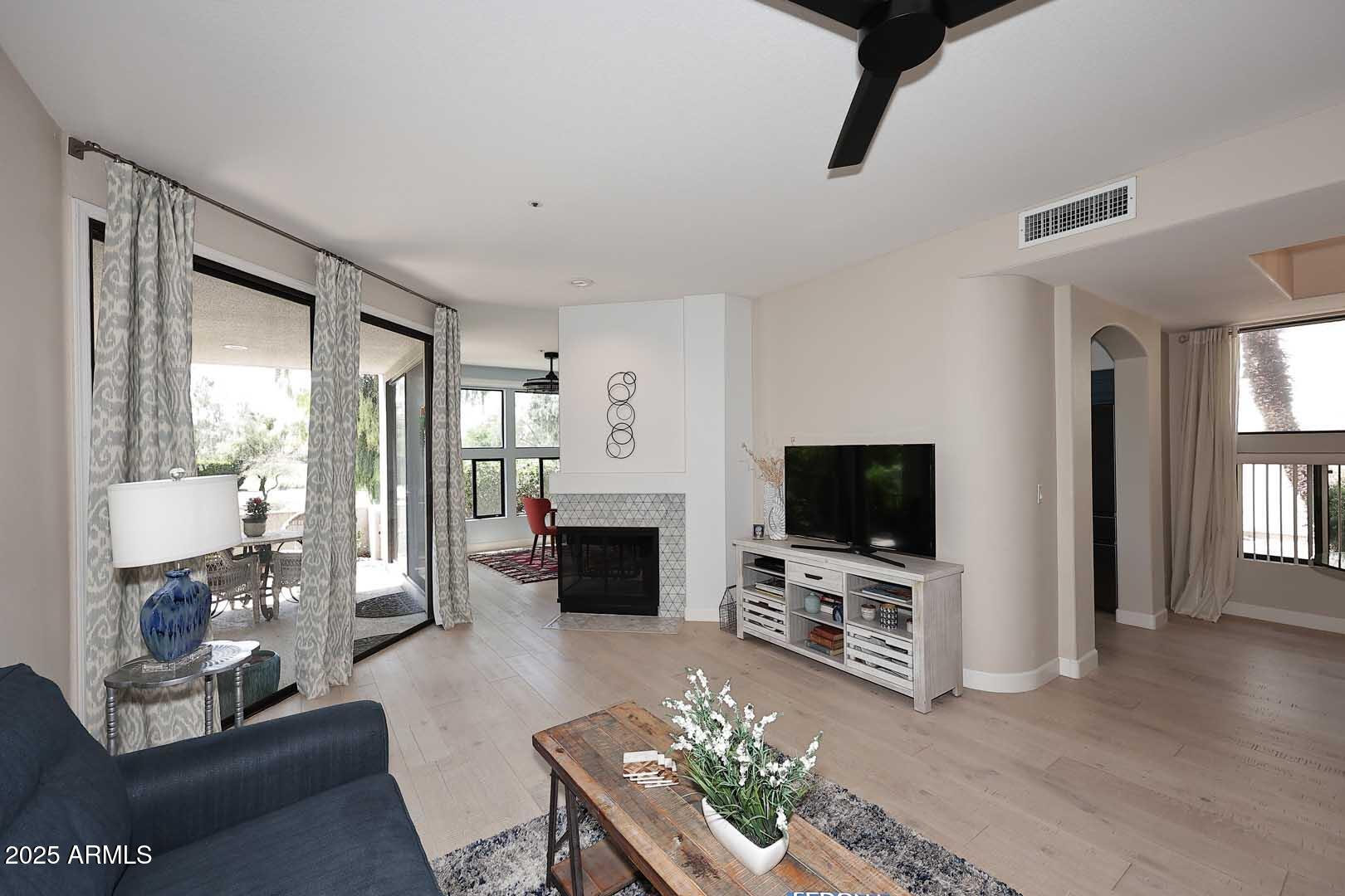7700 East Gainey Ranch Road, Unit 128 Scottsdale, AZ 85258 - Photo 13 of 60 a living room with furniture a flat screen tv and a fireplace