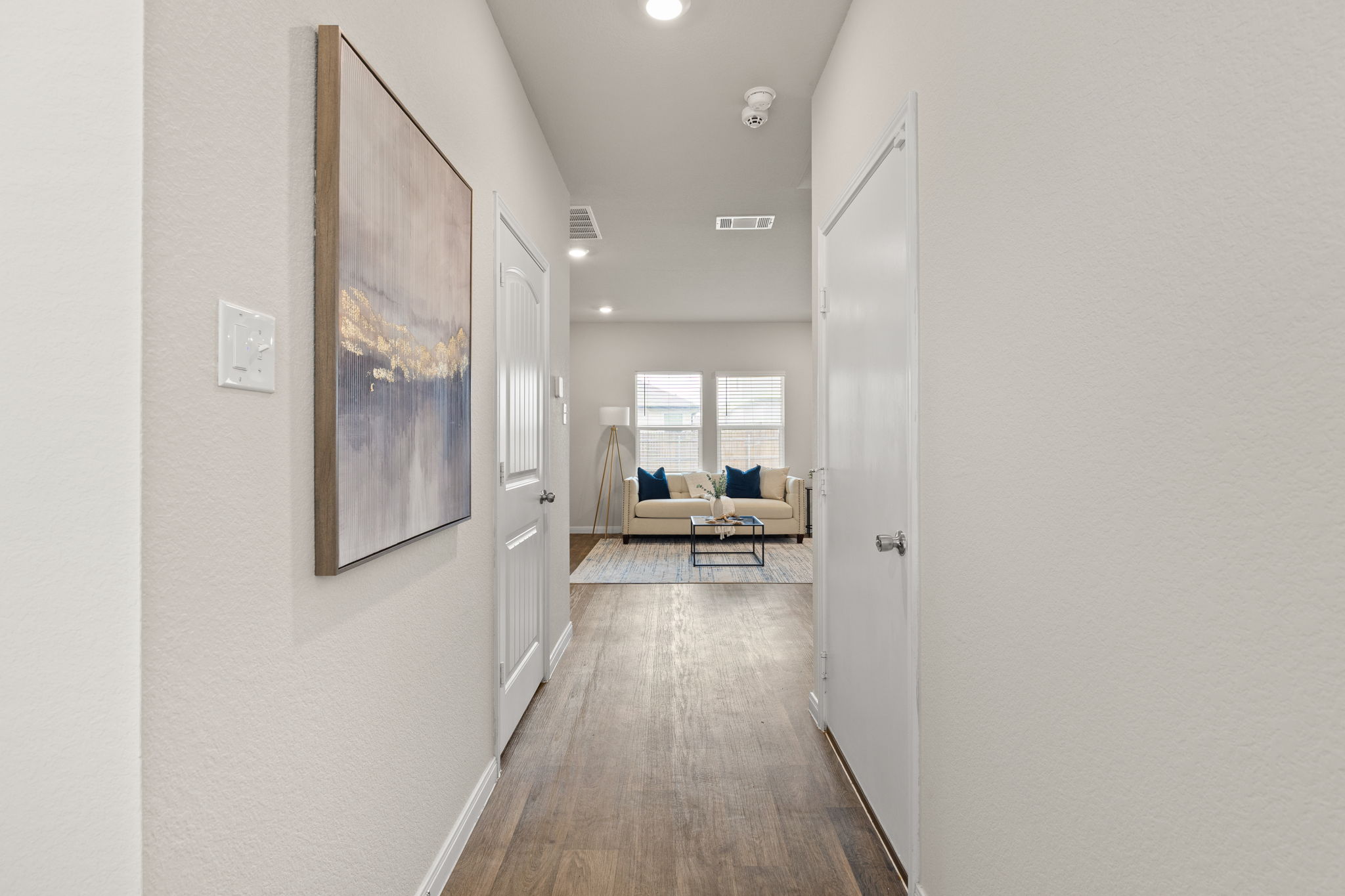 281 Jayden Drive Kyle, TX 78640 - Photo 6 of 36 Hallway with wood-finish flooring extending into the living space, featuring recessed lighting and white painted walls