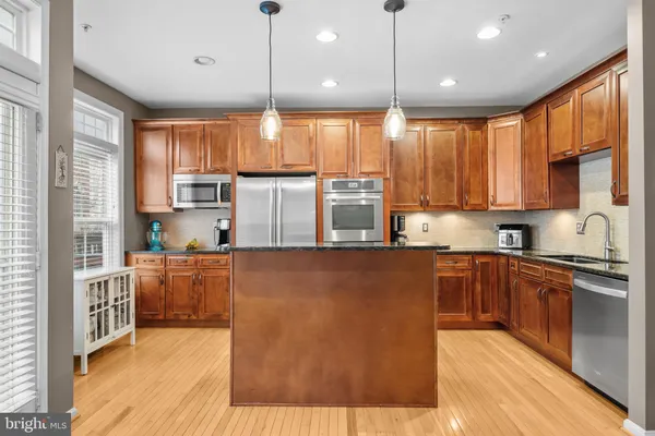 a kitchen with stainless steel appliances granite countertop a stove top oven a sink dishwasher a dining table and chairs with wooden floor