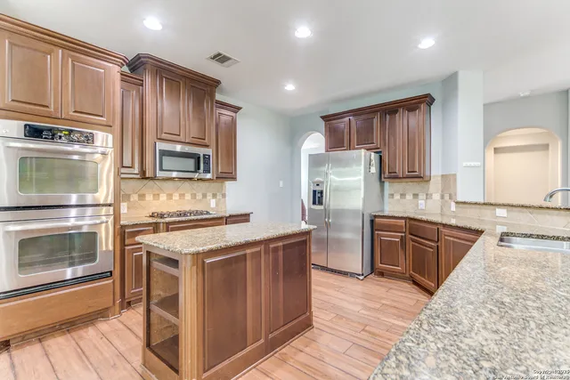 a kitchen with kitchen island granite countertop wooden cabinets stainless steel appliances and a counter space