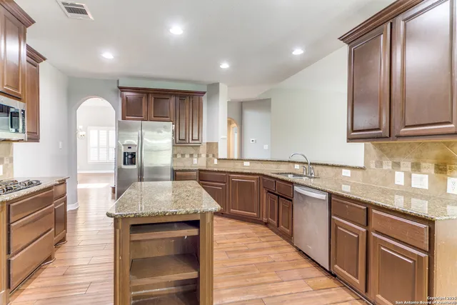 a kitchen with stainless steel appliances granite countertop stove top oven and cabinets