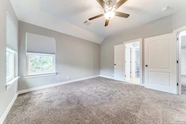 an empty room with windows and fan