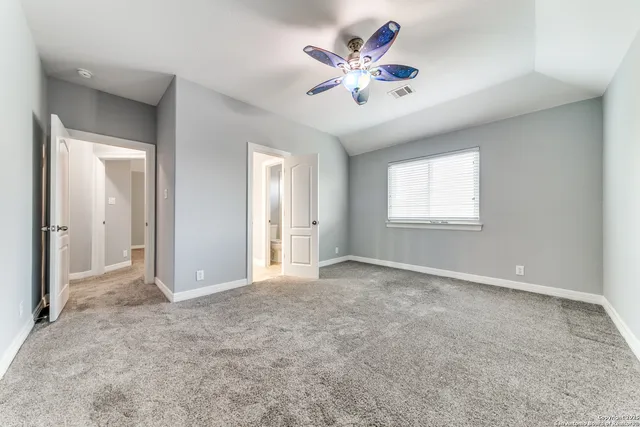 an empty room with chandelier fan and windows