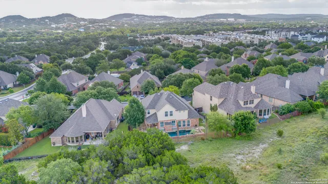 an aerial view of residential houses with outdoor space and trees