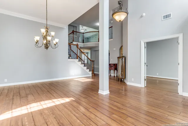 a view of a room with wooden floor chandelier and a chandelier