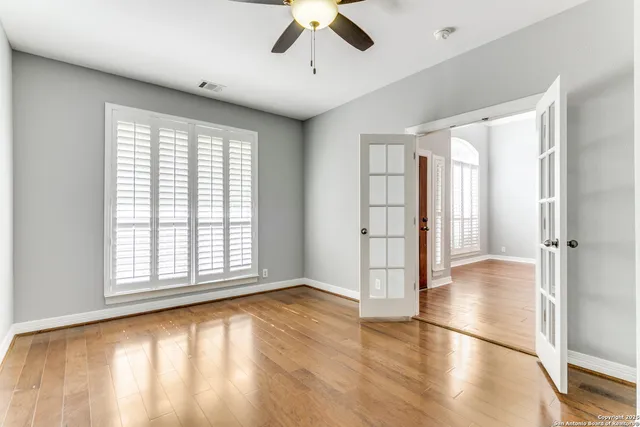 a view of empty room with wooden floor and fan
