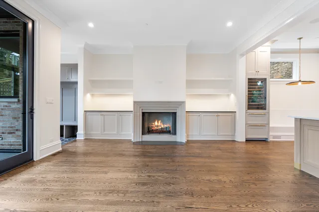 an empty room with wooden floor fireplace and windows