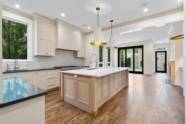 a large kitchen with granite countertop a stove a sink a center island and windows