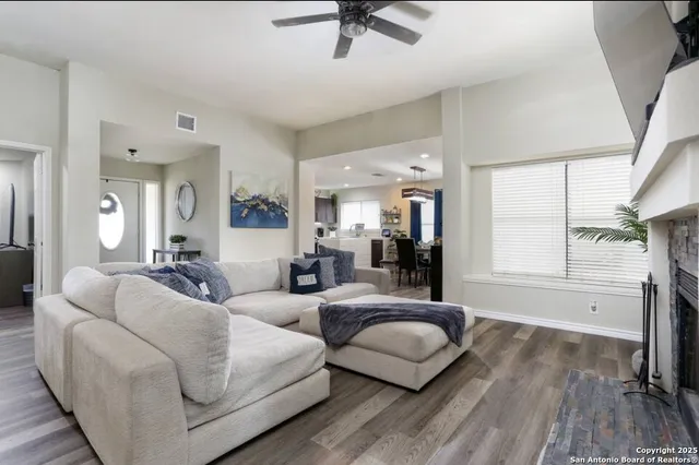 a living room with couches and a flat screen tv with kitchen view