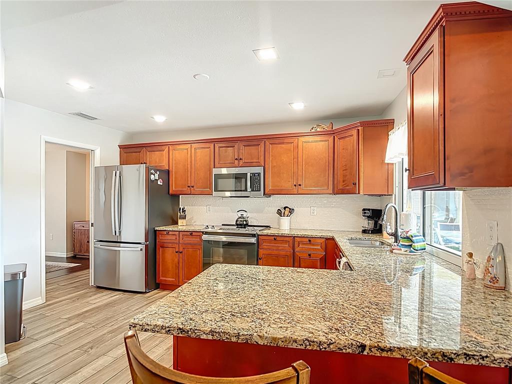 10253 Winstead Avenue Englewood, FL 34224 - Photo 21 of 46 a kitchen with stainless steel appliances granite countertop a refrigerator sink and wooden cabinets