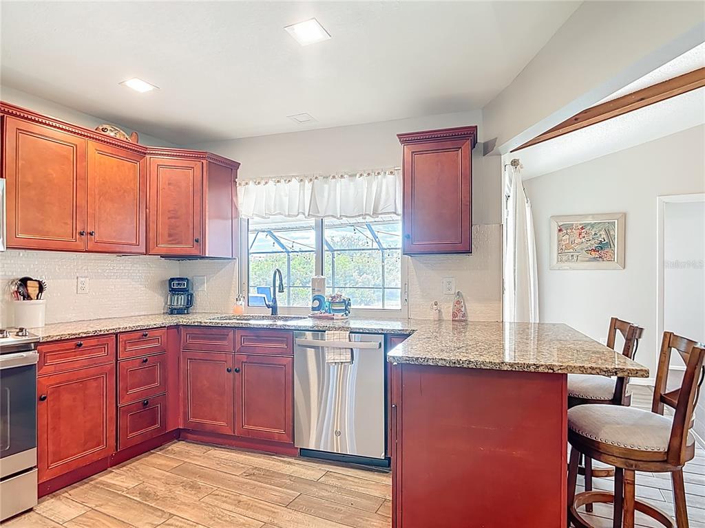 10253 Winstead Avenue Englewood, FL 34224 - Photo 23 of 46 a kitchen with granite countertop a sink stove and cabinets