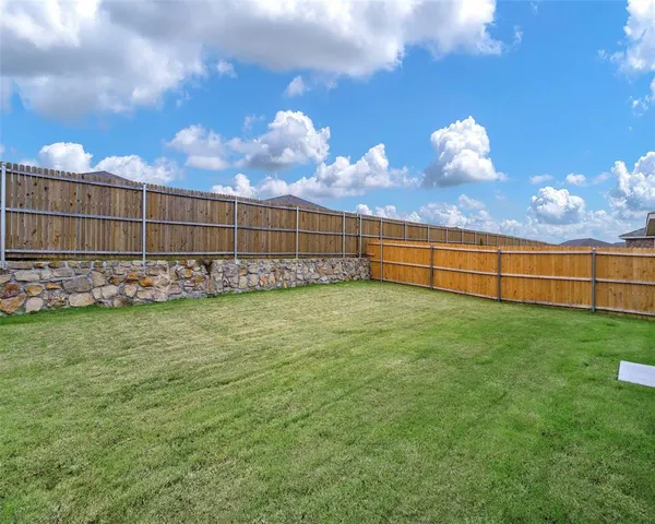 a view of a backyard with a large tree and wooden fence